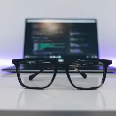 Okulary na biurku, przed laptopem z kodem. Idealne do pracy nad zmiennymi środowiskowymi w Windows.