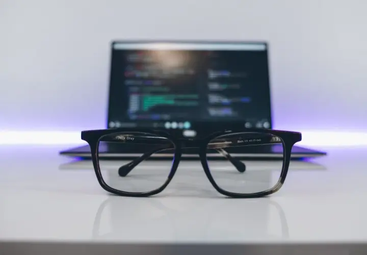 Okulary na biurku, przed laptopem z kodem. Idealne do pracy nad zmiennymi środowiskowymi w Windows.