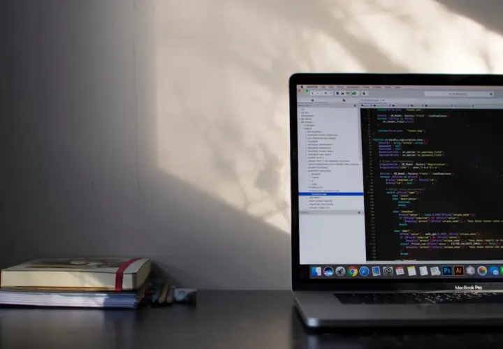 Na biurku leży stos książek, obok nich laptop z kodem PHP. Pętla `do while` jest widoczna na ekranie, gdzie programista pracuje nad projektem.