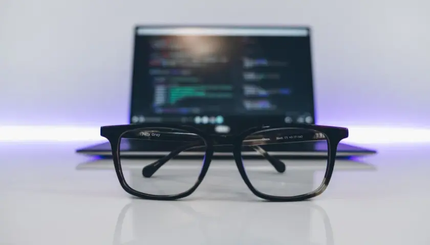 Okulary na biurku, przed laptopem z kodem. Idealne do pracy nad zmiennymi środowiskowymi w Windows.
