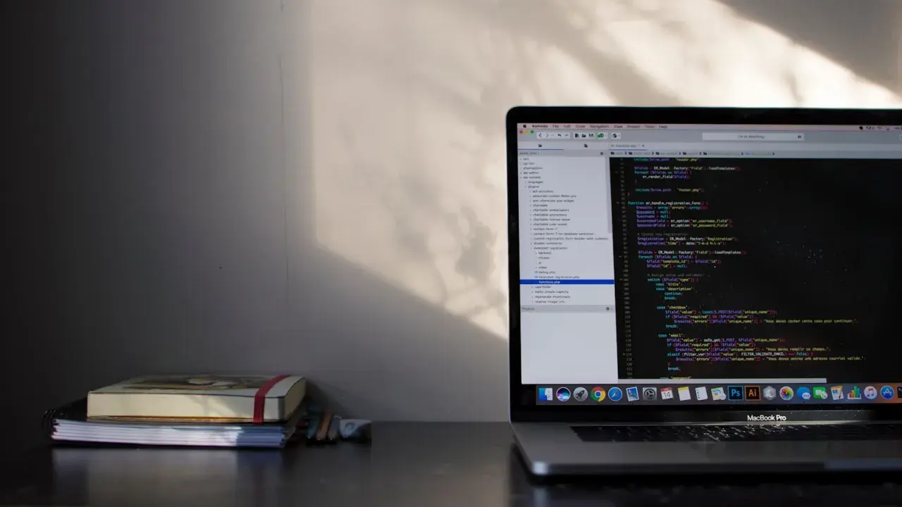 Na biurku leży stos książek, obok nich laptop z kodem PHP. Pętla `do while` jest widoczna na ekranie, gdzie programista pracuje nad projektem.
