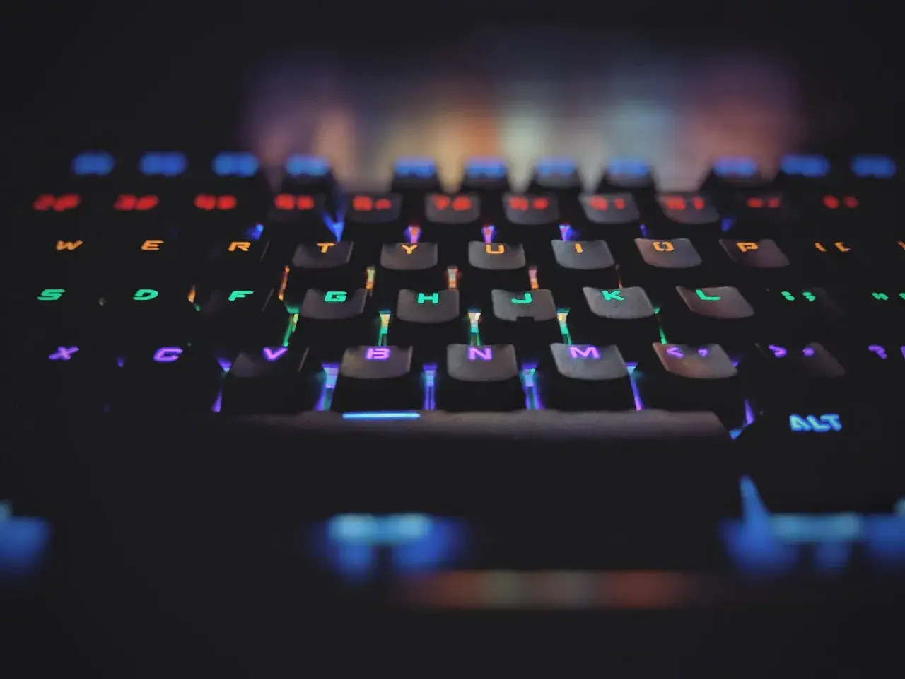 Klawiatura gamingowa z podświetleniem RGB. Każdy klawisz świeci innym kolorem, symbolizując zasadę open-closed principle w kodzie.